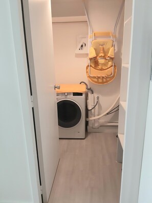 Une petite salle de bain équipée d’un lave-linge, de toilettes et d’un espace douche.