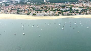 Vue aérienne d’une ville côtière avec une plage et de nombreux bateaux sur l’eau.