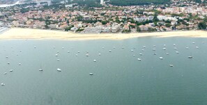 Vue aérienne d’une ville côtière avec une plage et de nombreux bateaux sur l’eau.