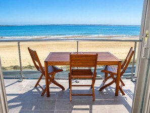 Un balcon avec une table et des chaises donnant sur une plage.