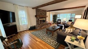 A living room with a stone fireplace, wooden floors, a television, and a sofa.