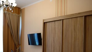 A room with a wooden desk, a television mounted on the wall, a wardrobe, and a patterned floor. - Barock Jimbolia (Jimbolia)
