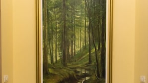 A framed painting of a forest scene on a wall, a bench, and a vase with flowers. - Barock Jimbolia (Jimbolia)