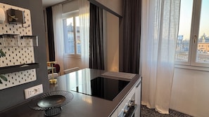 A modern kitchen with a built-in stove, a dining table, and a window with curtains.