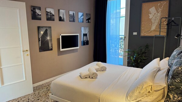A hotel room with a bed, a flat-screen TV, and a cityscape view. - Appartamenti Miro  (Treviso)