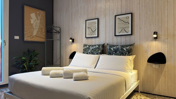 A modern bedroom with a bed, pillows, and artwork on the wall.