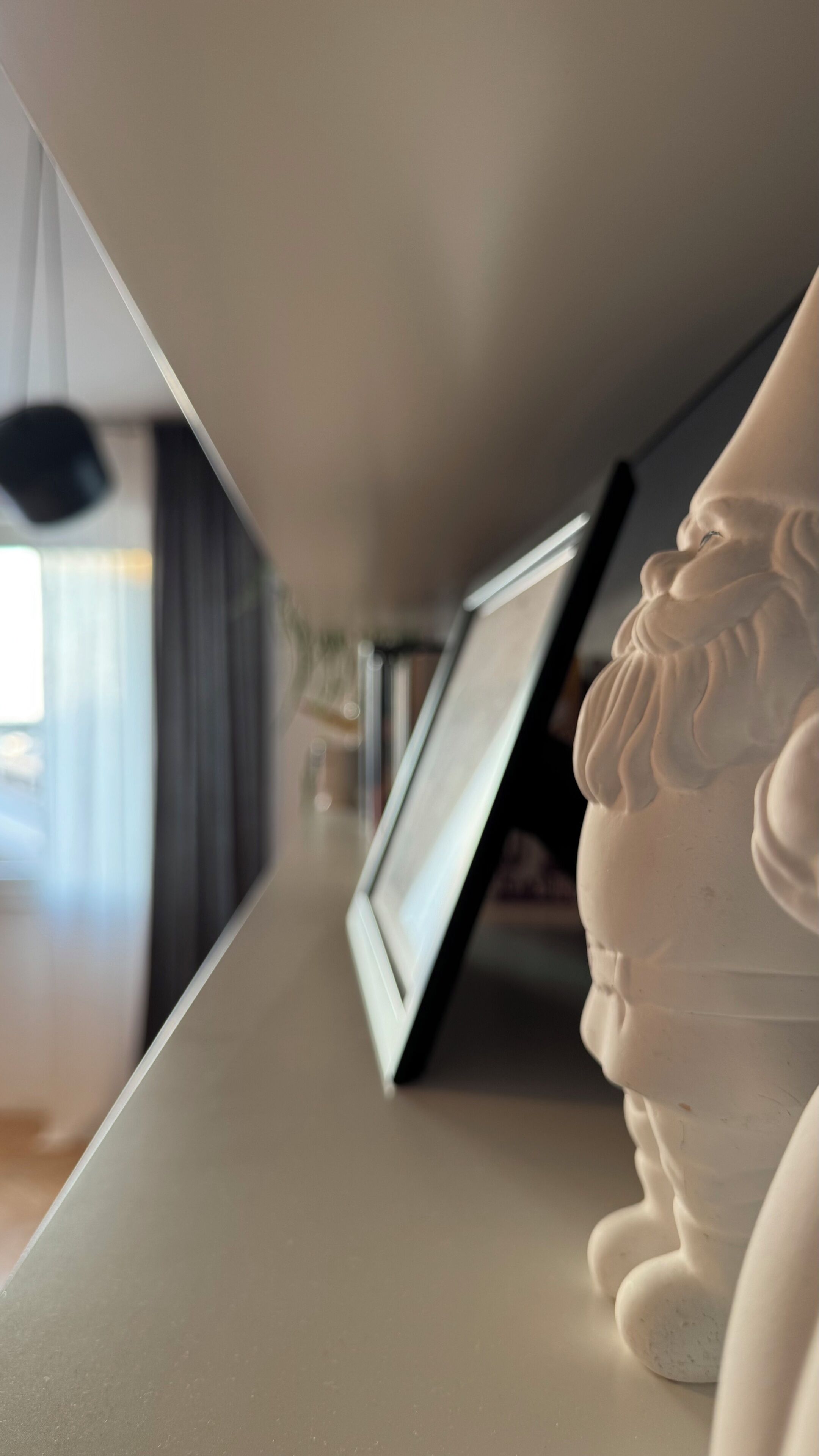 Une pièce avec une table blanche, un tableau encadré et une sculpture blanche.