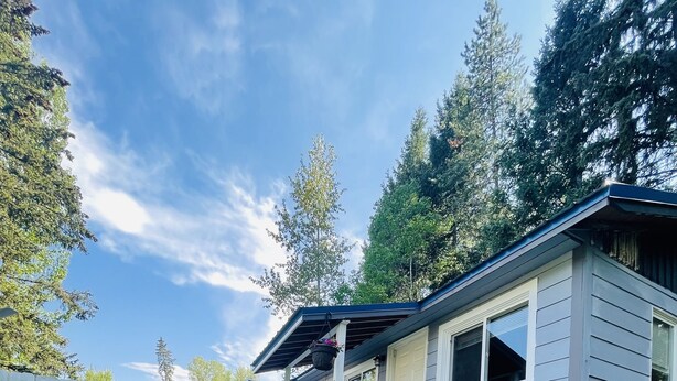 A single-story house with a covered porch, a stone pathway, and a white picket fence. - Mountain Bungalow (Martin City)