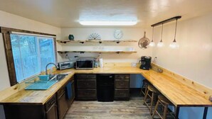A compact kitchen with a wooden countertop, a microwave, a coffee maker, and a sink. - Mountain Bungalow (Martin City)