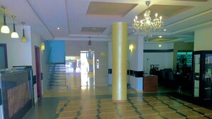 Un hall amplio con piso a cuadros, una recepción, una escalera y un candelabro.