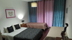Un dormitorio con cama, mesita de noche, lámpara y una pequeña mesa con un objeto decorativo.