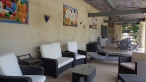 An outdoor seating area with sofas and tables, a covered section, and artwork on the walls. - Appartement de caractère dans un mas provençal (Jonquières)