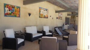 A lounge area with multiple seating options including sofas and armchairs, a large pillar, and artwork on the walls. - Appartement de caractère dans un mas provençal (Jonquières)