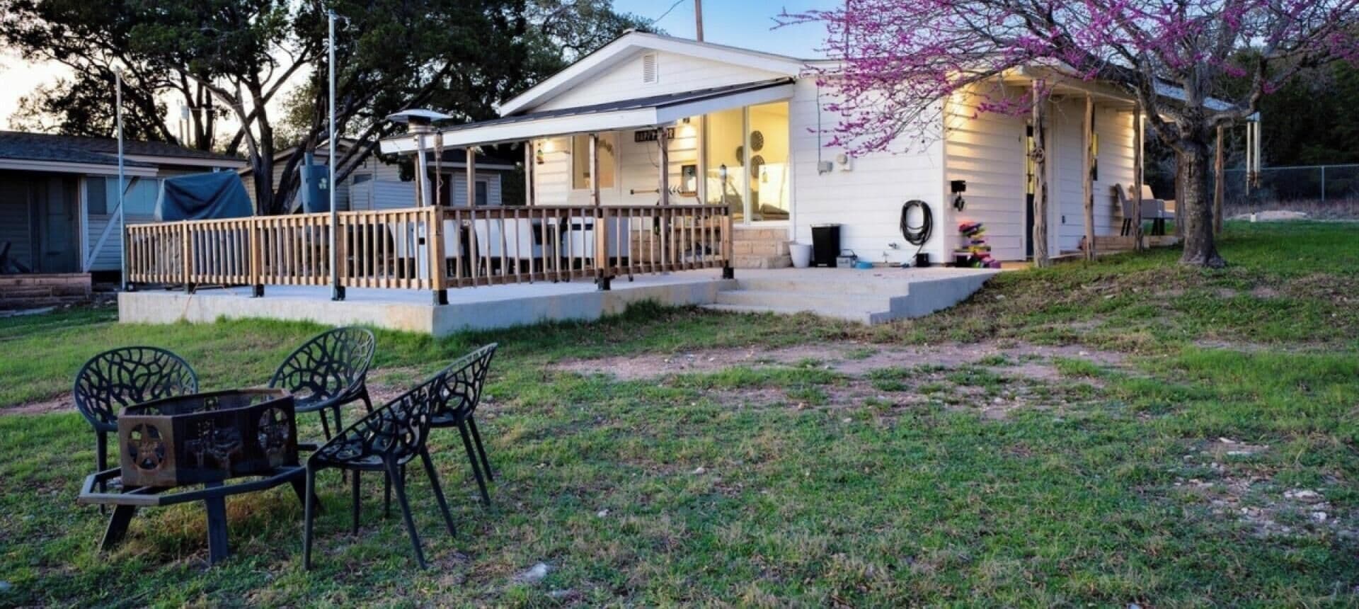 A house with a covered porch, a small deck, and a lawn with chairs.