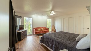 A bedroom with a bed, a dresser, a red sofa, and a chair. - 4 Bedroom + 3.5 Bathroom Greers Ferry Lakefront Home in Heber Springs! (Heber Springs)