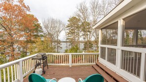 A wooden deck with two green chairs and a small table, overlooking a lake with trees in the background. - 4 Bedroom + 3.5 Bathroom Greers Ferry Lakefront Home in Heber Springs! (Heber Springs)