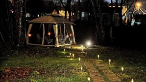 A tented outdoor area with a paved walkway and multiple ground lights.
