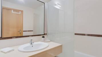 Un baño con lavamanos, espejo y ducha.