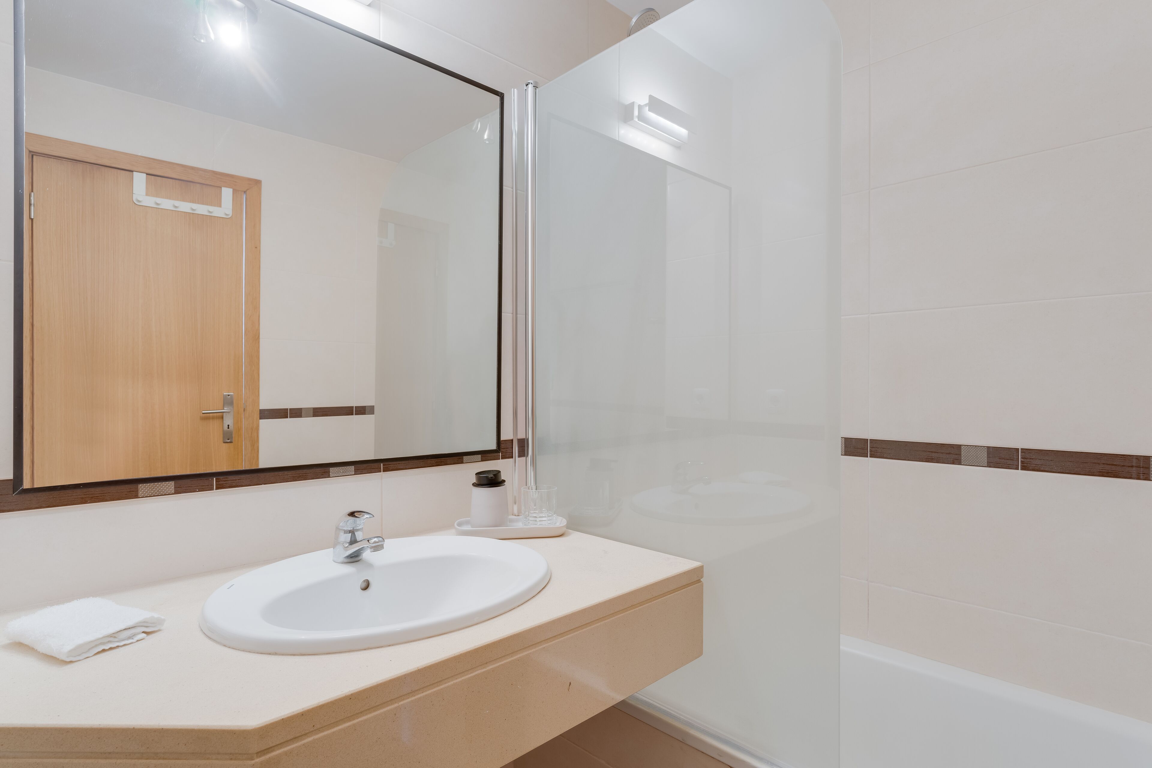 Un bagno moderno con lavandino bianco, specchio e cabina doccia in vetro.
