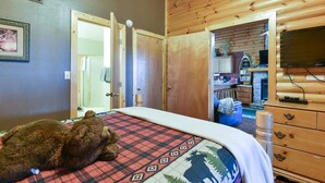 Ein Schlafzimmer mit einem Bett, einem Teddybären, einer hölzernen Kommode und einem Fernseher.