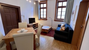 Een woonkamer met een houten eettafel, een bank en een televisie.