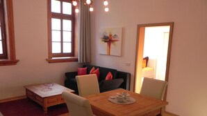 Een eethoek met een houten tafel en stoelen, een bijzettafeltje en een raam met gordijnen.