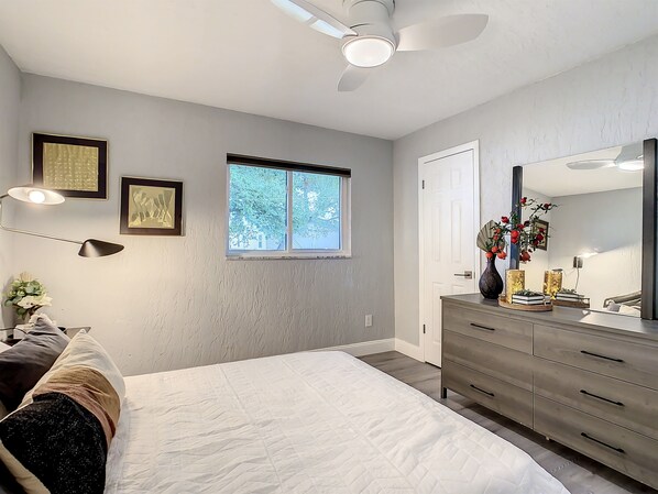 Une chambre à coucher avec un lit, une commode et un ventilateur de plafond.