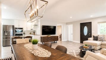 A modern living room with a wooden dining table, a sofa, and a TV.