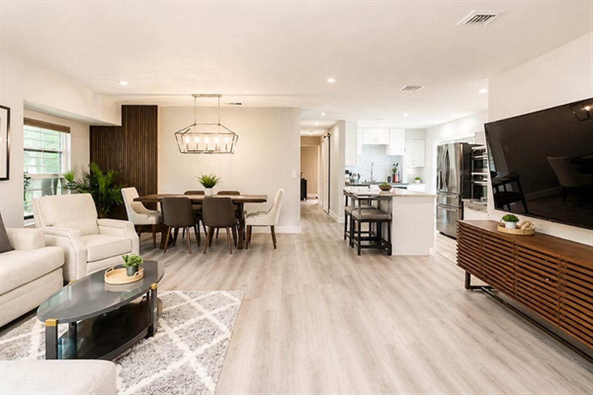 A modern living room with a dining area, kitchen, and a TV.