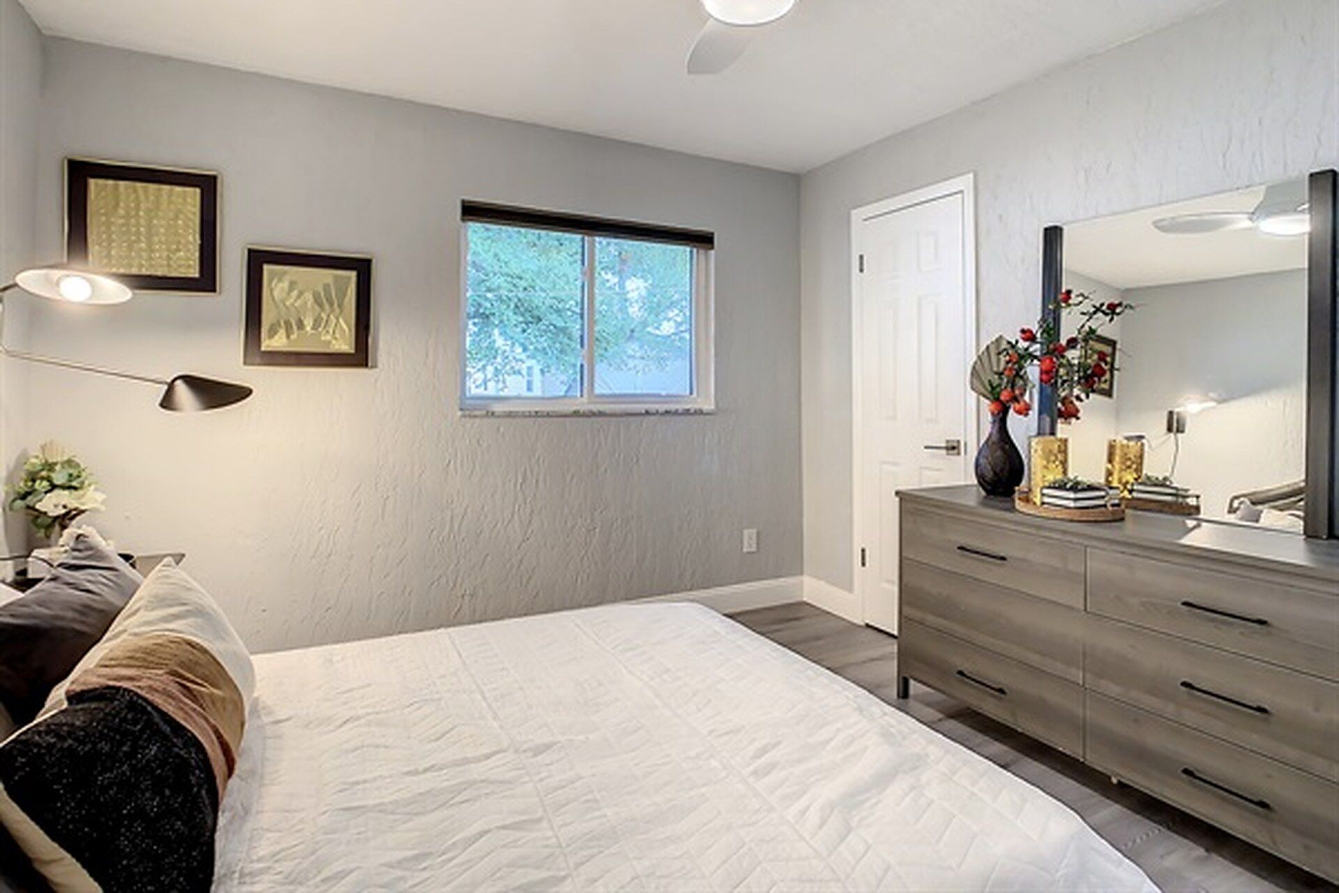 A bedroom with a bed, dresser, and a window.