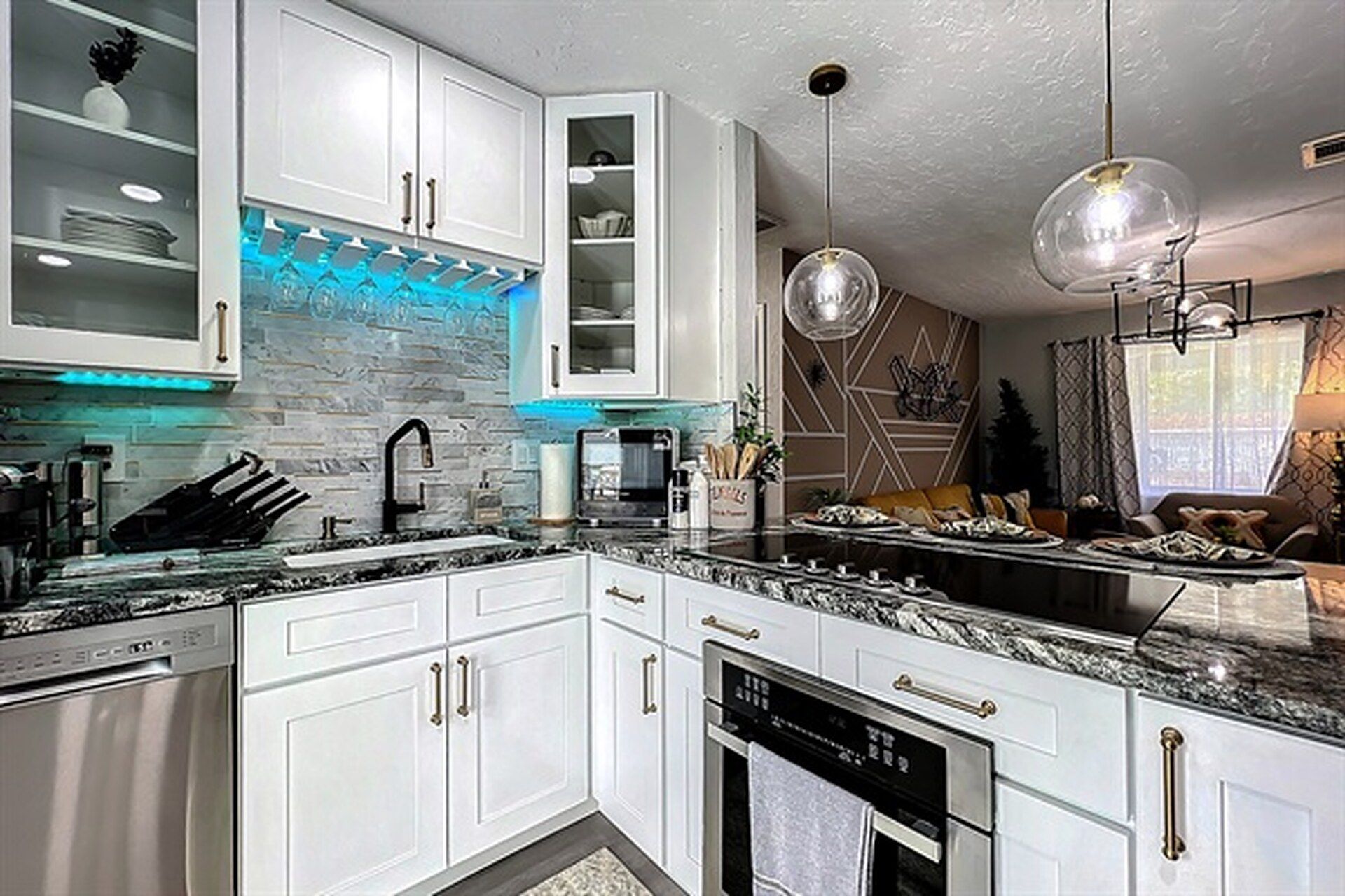 A modern kitchen with white cabinetry, a granite countertop, and a built-in dishwasher.