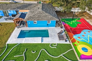 Una propiedad residencial con piscina, una casa azul y un área exterior colorida.