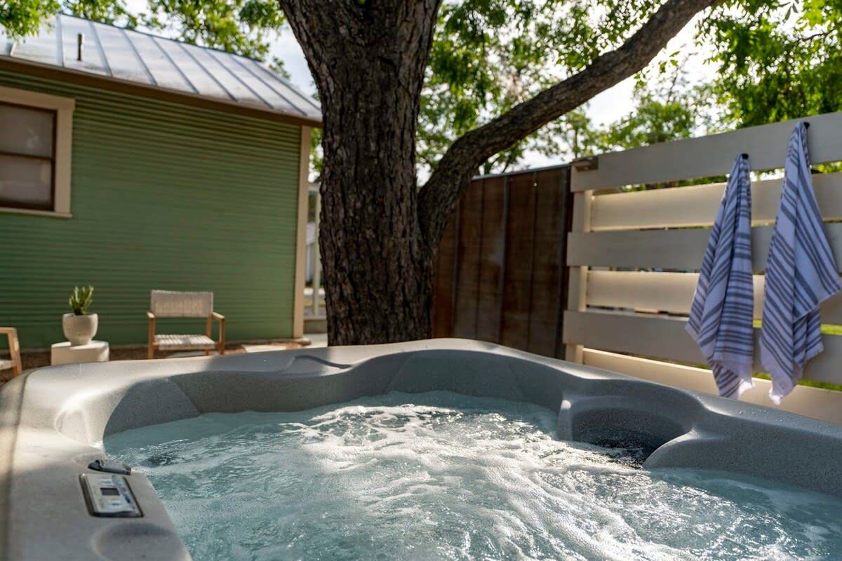 A hot tub with a tree and a wooden fence in the background.