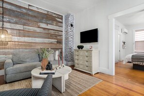 Ein modernes Wohnzimmer mit einem grauen Sofa, einem Couchtisch und einem an der Wand befestigten Fernseher.