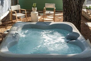 Ein Whirlpool mit Bedienfeld, umgeben von Gartenmöbeln und einem Baum.