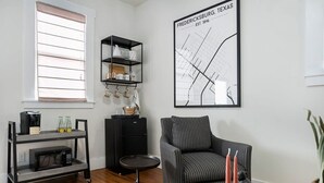 Ein modernes Wohnzimmer mit einem schwarzen Metallwagen, einem schwarzen Sofa, einer Kaffeemaschine und einer Karte von Fredericksburg, Texas.