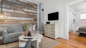 Ein modernes Wohnzimmer mit einem grauen Sofa, einem weißen Couchtisch und einem an der Wand befestigten Fernseher.