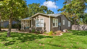 A single-story house with a front porch, a small front yard, and a wooden fence.