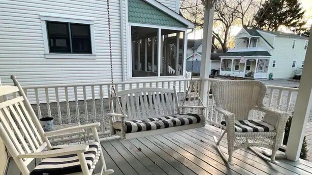 A wooden deck with rocking chairs and a bench, overlooking a residential area. - Beautiful home in Chautauqua community - linens, parking, washer Included (Lakeside Marblehead)