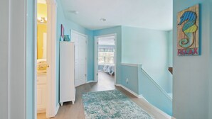A hallway with light blue walls, a patterned rug, and a seahorse artwork. - Beautiful home in Chautauqua community - linens, parking, washer Included (Lakeside Marblehead)