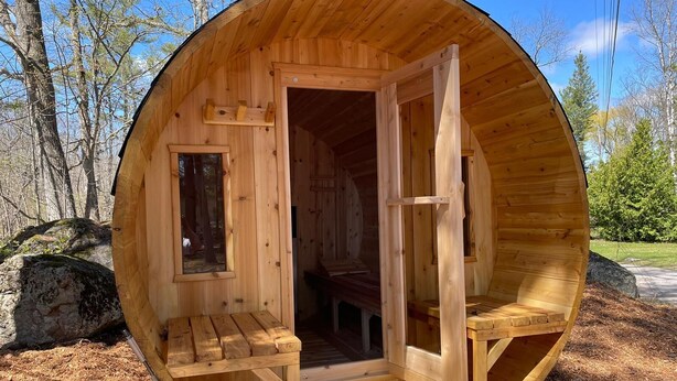 Una cabaña de madera con un diseño circular, que incluye un banco y una puerta.