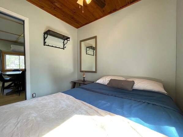 A bedroom with a bed, a desk, and a chair.