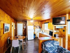 A compact cabin with a dining area, kitchenette, and a bed.