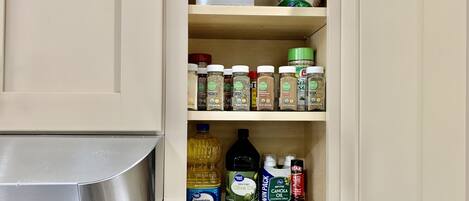 Un mueble de cocina con diferentes alimentos y aceites de cocina.
