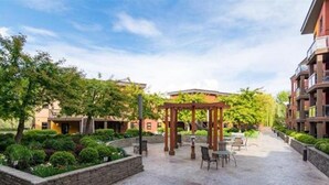 A courtyard with a pergola, seating area, and well-maintained landscaping. - Playa Del Sol Retreat 550 | Pool + Hot Tub | (Kelowna)