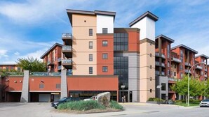A multi-story residential building with balconies, a garage, and a landscaped area in front. - Playa Del Sol Retreat 550 | Pool + Hot Tub | (Kelowna)