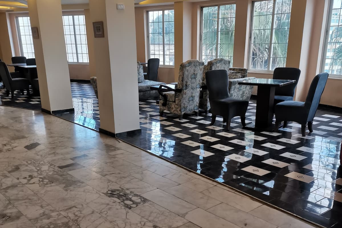 A spacious lobby with a checkered floor, seating area with chairs and tables, and large windows with natural light.