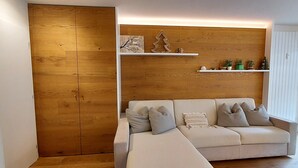 A modern living room with a wooden wall, a sofa, and a white console table. - Fié allo Sciliar (Alpe di Siusi Val Gardena) (Fiè allo Sciliar)