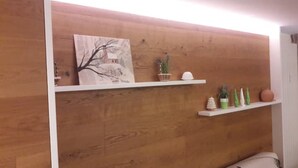 A wooden wall with two white shelves; one holds a framed picture and a small plant, the other has decorative items and a small tree. - Fié allo Sciliar (Alpe di Siusi Val Gardena) (Fiè allo Sciliar)