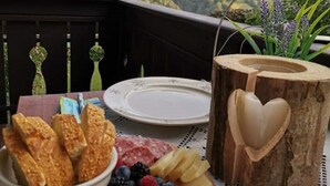 A wooden table with a cheese platter, bread, and a heart-shaped wooden bowl on a balcony overlooking a scenic landscape. - Fié allo Sciliar (Alpe di Siusi Val Gardena) (Fiè allo Sciliar)